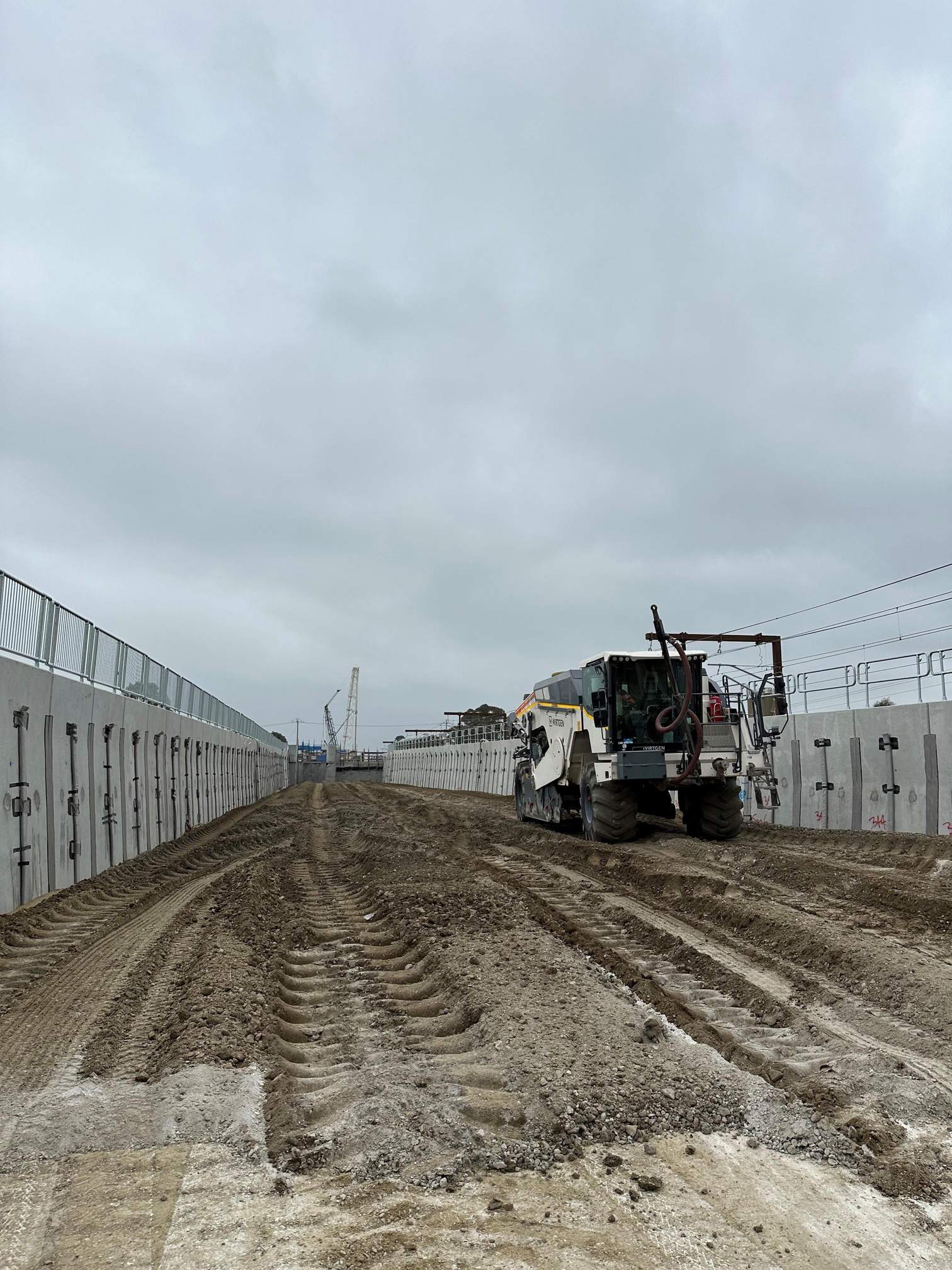 Grader working the rail corridor between concrete walls at Pakenham